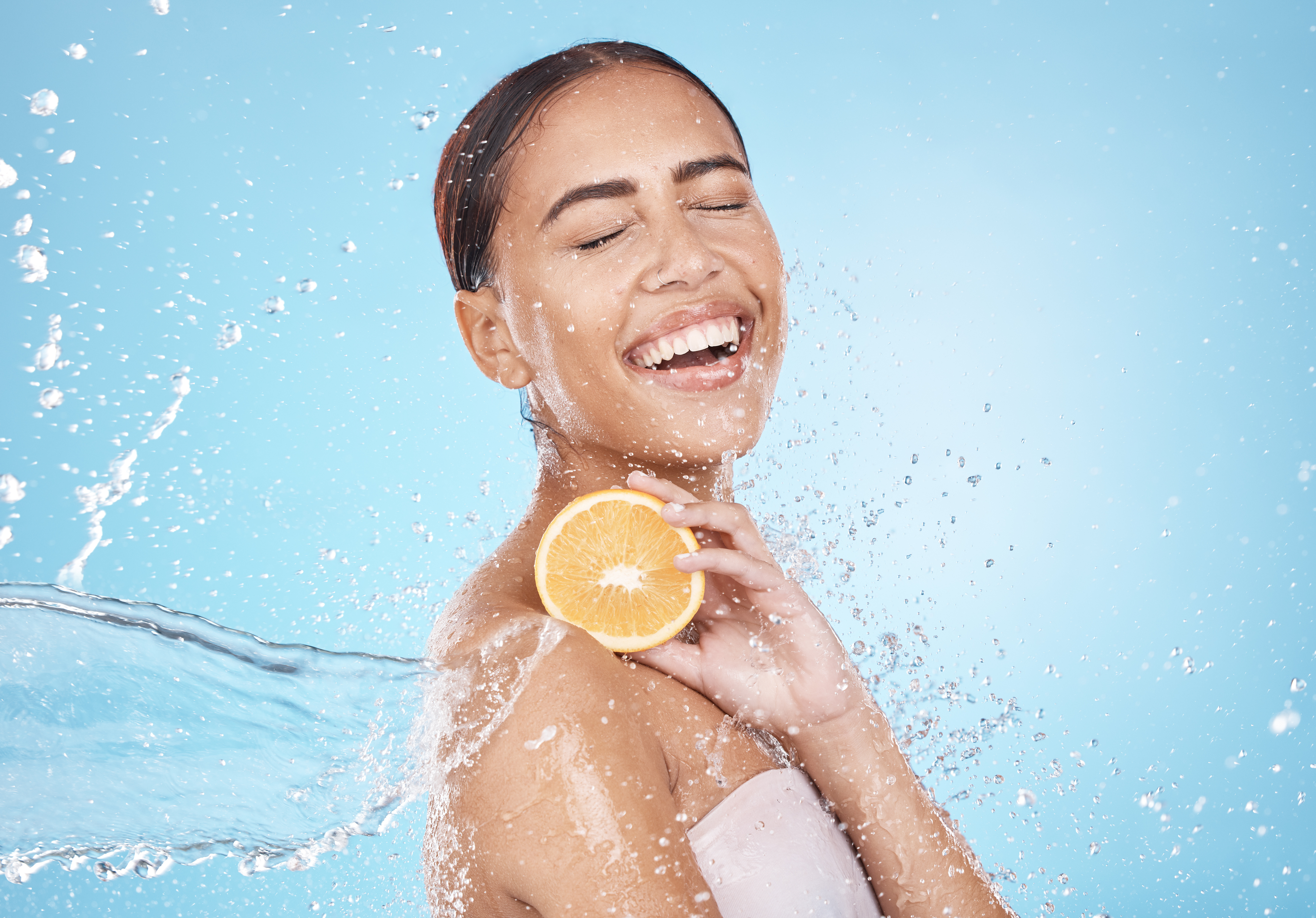 Water, lemon and woman with happy skincare, beauty or cosmetics product in studio or shower mockup for vegan advertising. Wellness model with fruit in hands and splash for healthy dermatology glow.